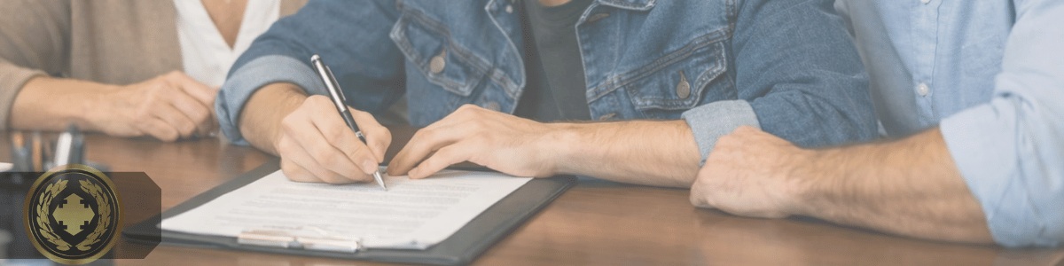 Adolescente assinando um documento em um cartório, sentado à mesa ao lado dos pais, que acompanham o momento com atenção